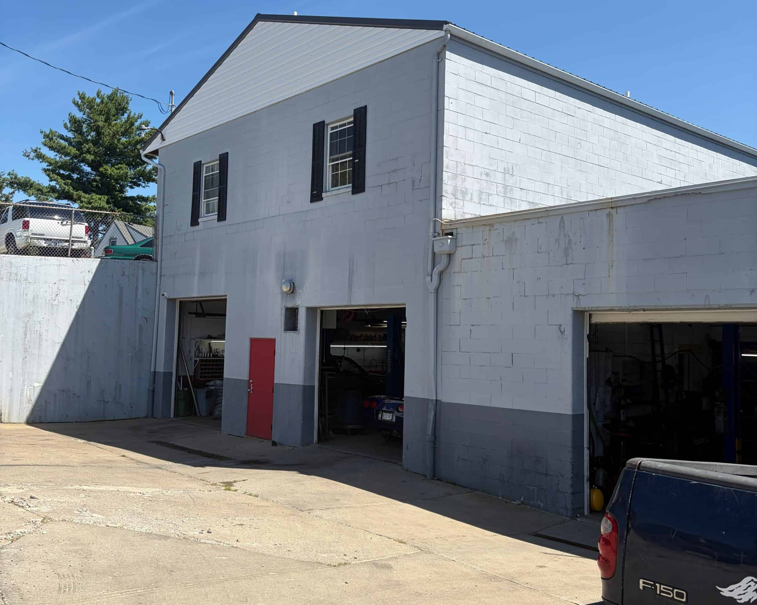 Auto repair shop exterior with garage bays and white building.