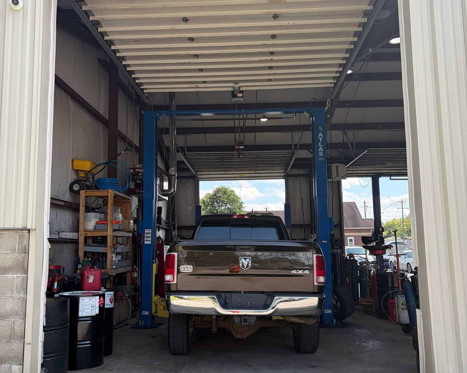 Inside auto repair shop with vehicle on lift and tools on shelves.